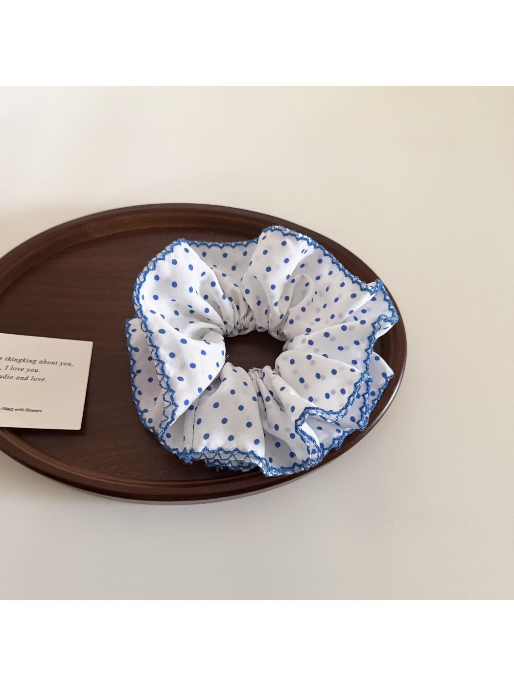 Blue scrunchie with white polka dots displayed on a wooden surface