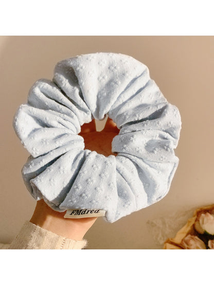 Side view of Gifty floral print scrunchie highlighting its elastic stretch and fabric folds