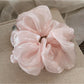 Multiple beige satin ruched scrunchies stacked together on a white background