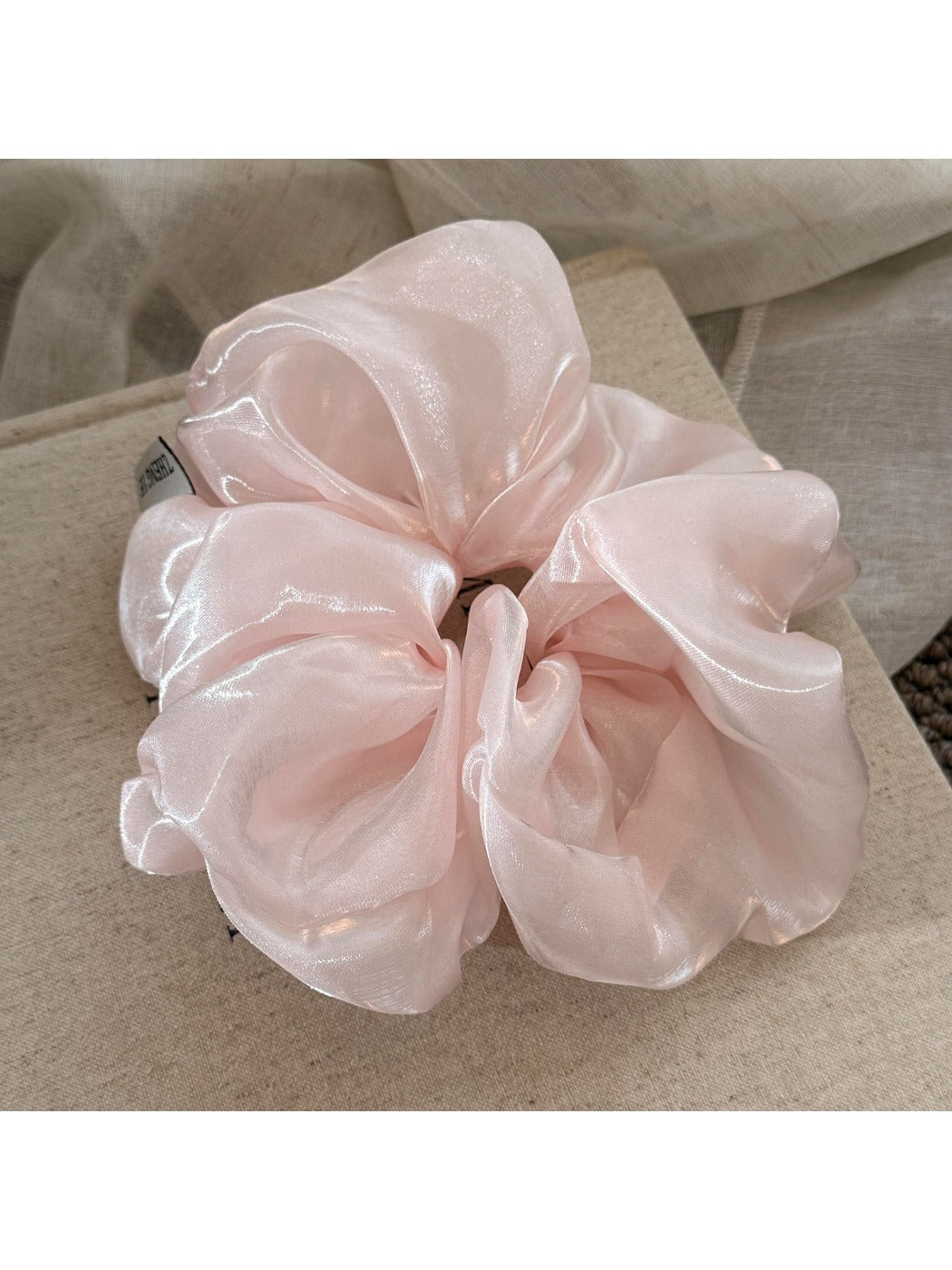 Multiple beige satin ruched scrunchies stacked together on a white background