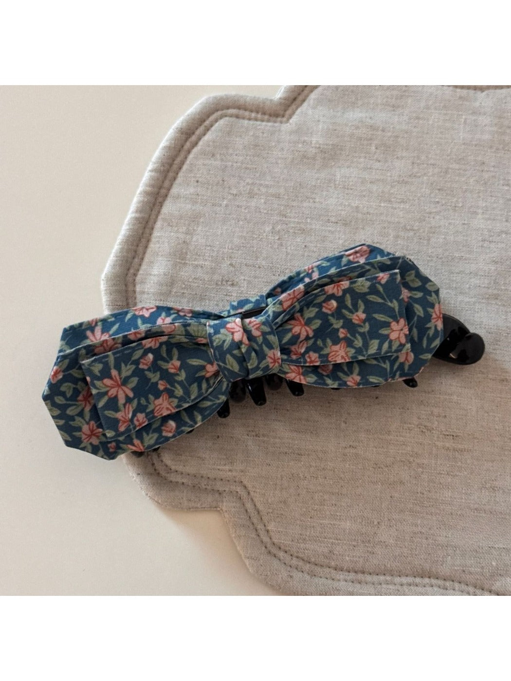 Side view of Beau bow hair clip highlighting its curved shape and painted fabric