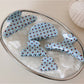 Blue hair clip with white polka dots on a white background