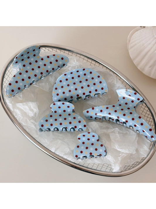 Blue hair clip with white polka dots on a white background