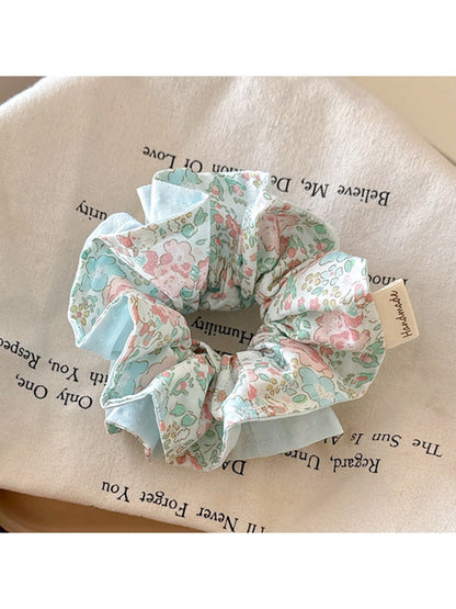 Blue ruffled scrunchie styled in a ponytail on dark hair