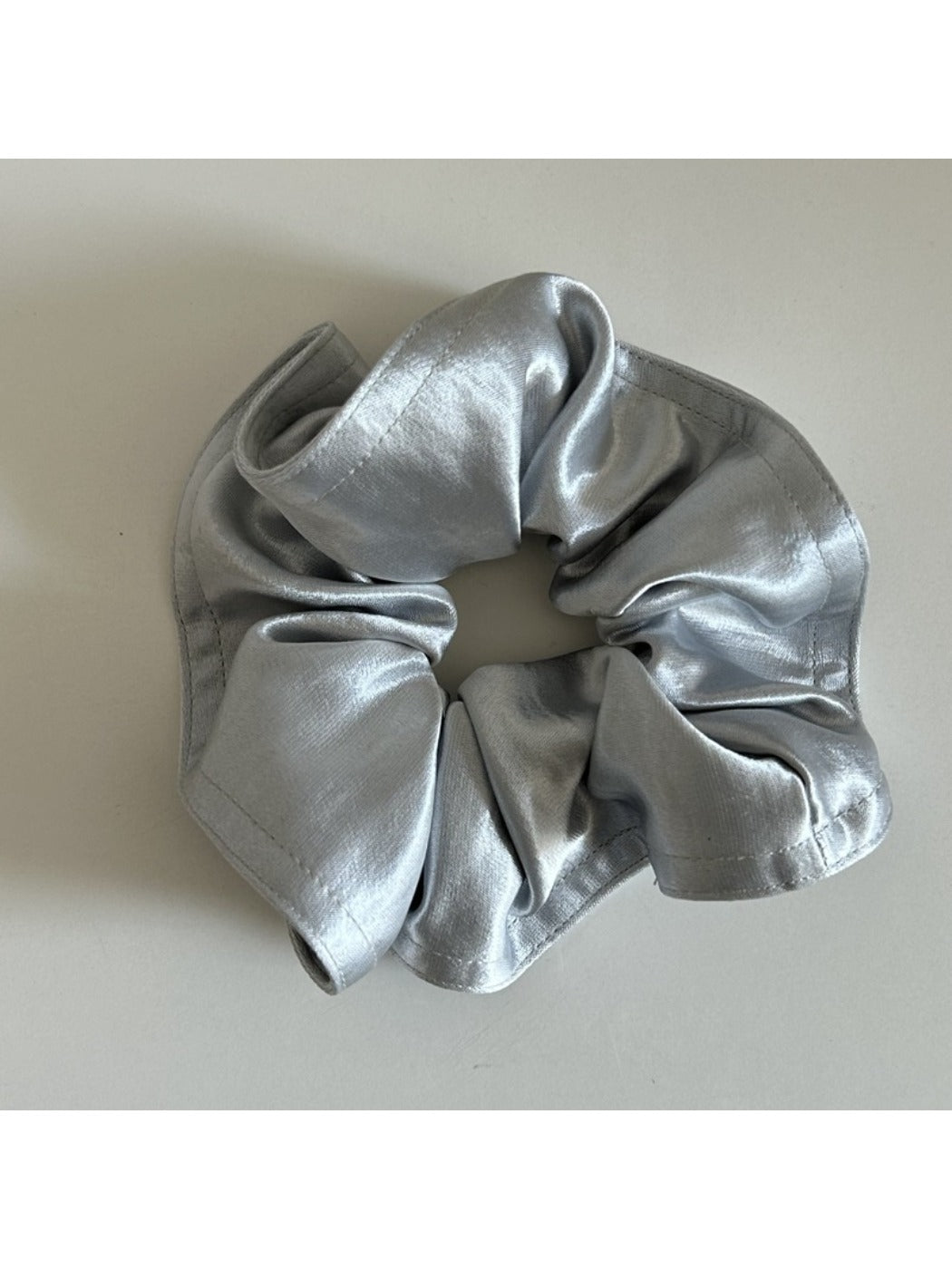 Gifty satin scrunchie paired with other hair accessories on a wooden surface