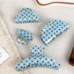 Close-up of blue polka dot hair claw clip showing curved teeth