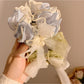 Close-up of delicate lace bow detail on soft pink hair tie
