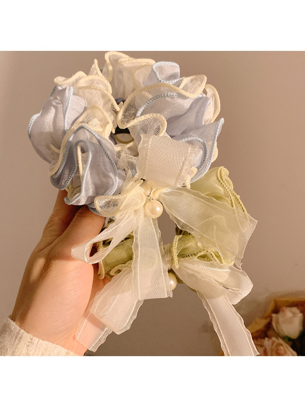 Close-up of delicate lace bow detail on soft pink hair tie