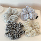 Close-up of Gifty elegant scrunchie with white daisy print on beige fabric