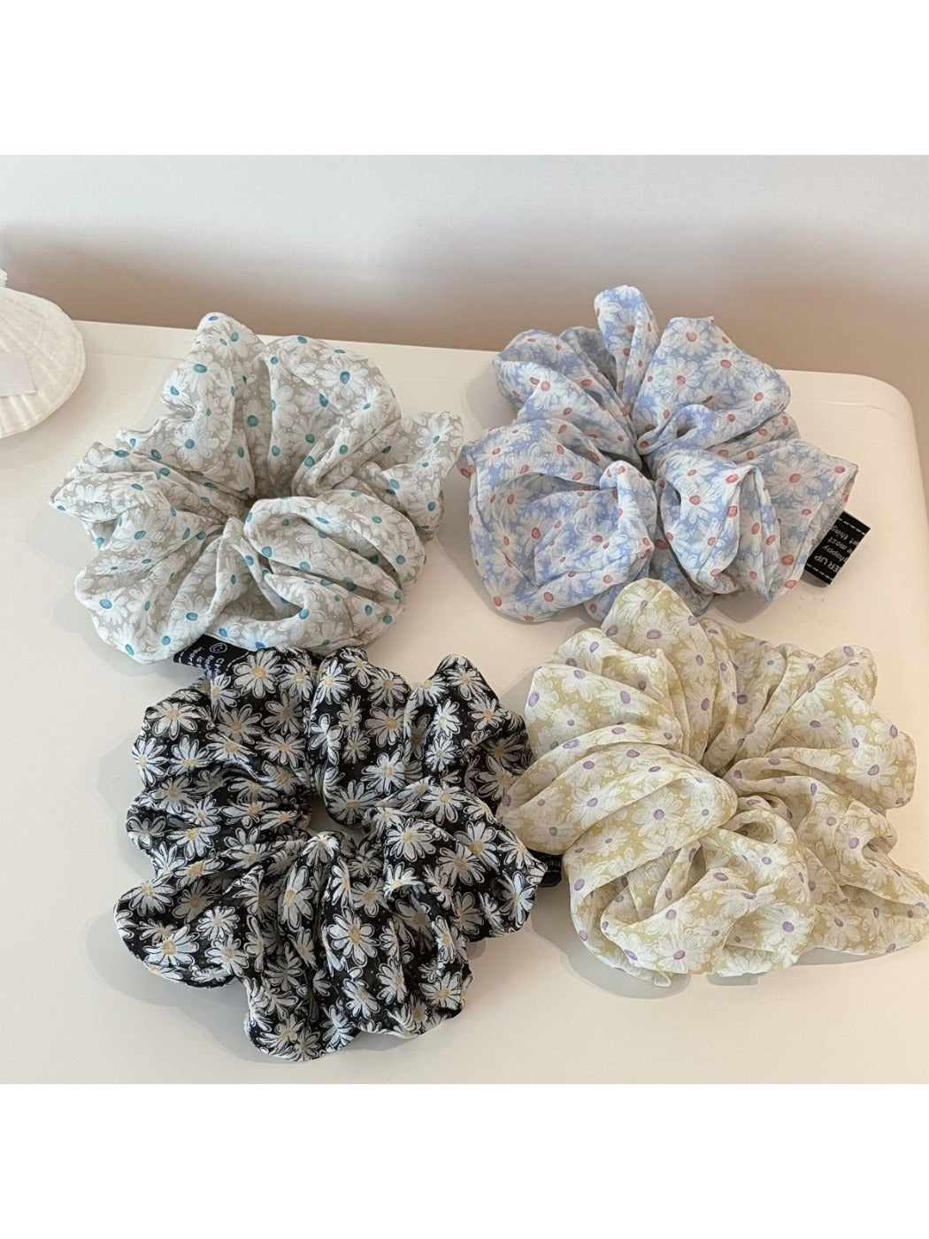 Close-up of Gifty elegant scrunchie with white daisy print on beige fabric
