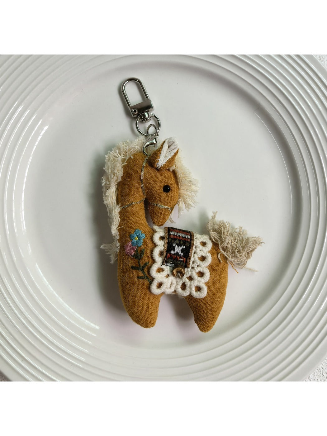 Fabric pony bag charm hanging from a backpack zipper pull
