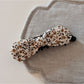 Beau bow hair clip styled in a ponytail, featuring blue and beige oil painting pattern