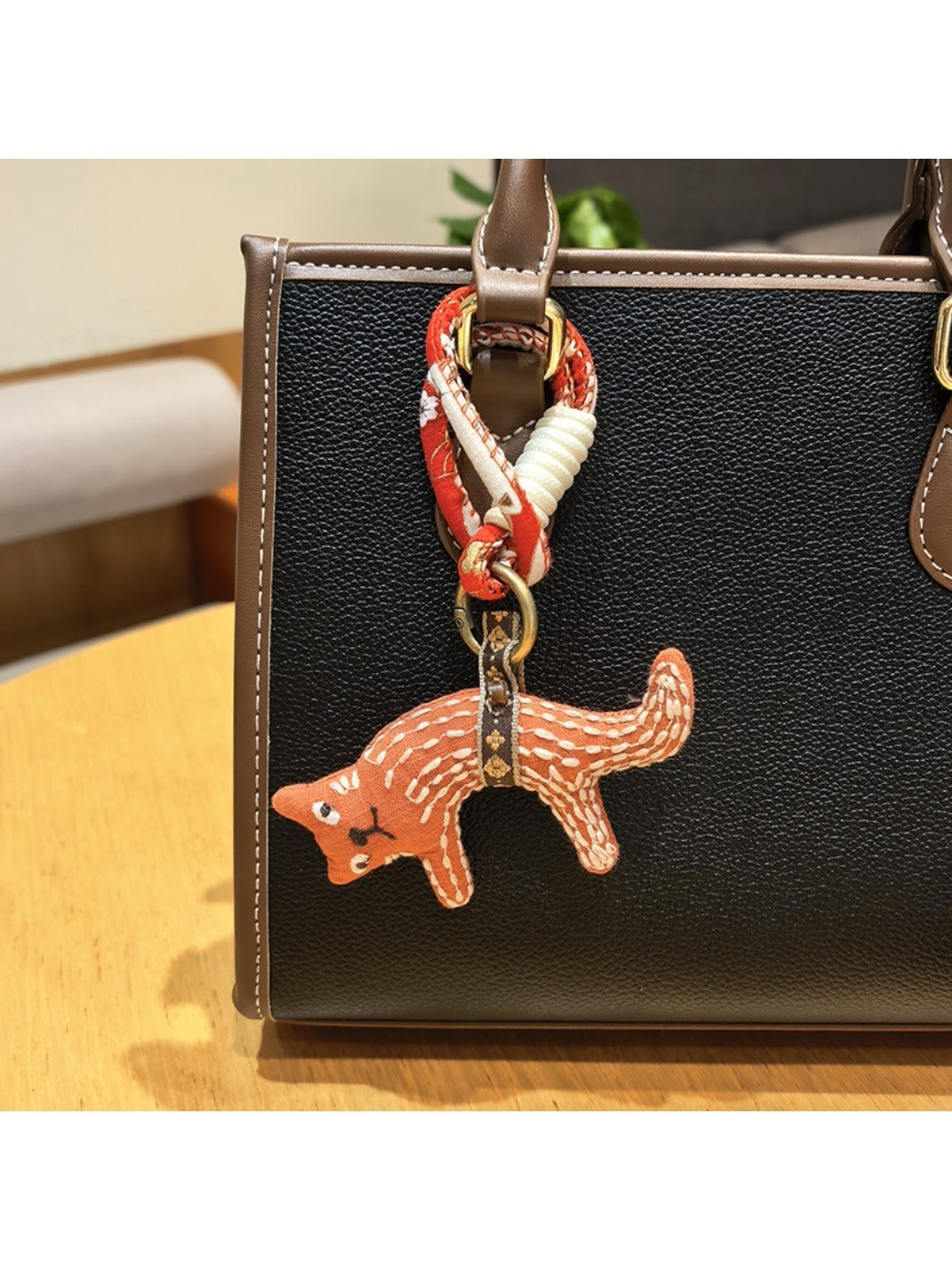 Fox charm keychain next to a small notebook and pen on a desk