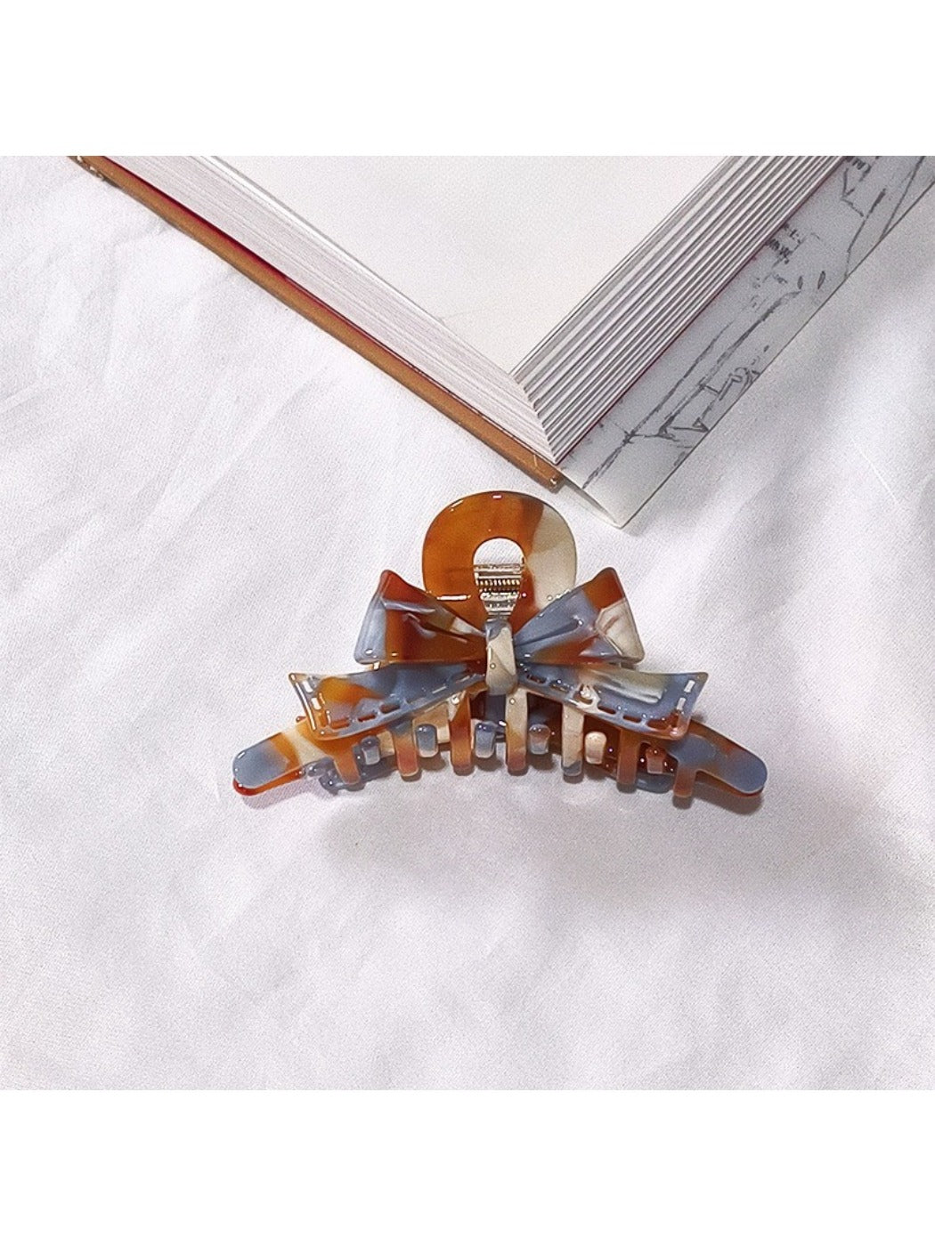 Beau acetate bow shaped claw clip open to show inner teeth and clasp