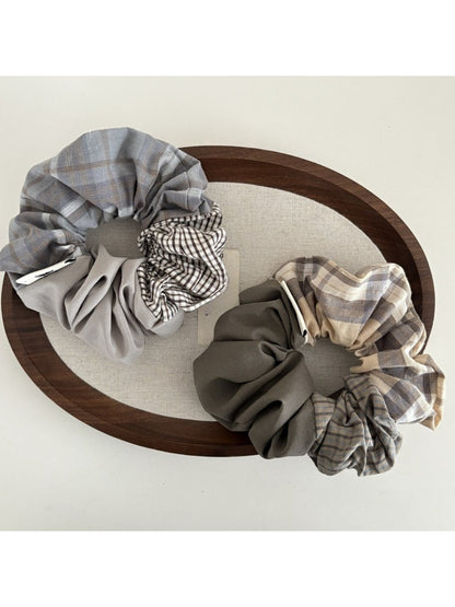 Gifty scrunchie styled on a wrist showing its patchwork plaid design