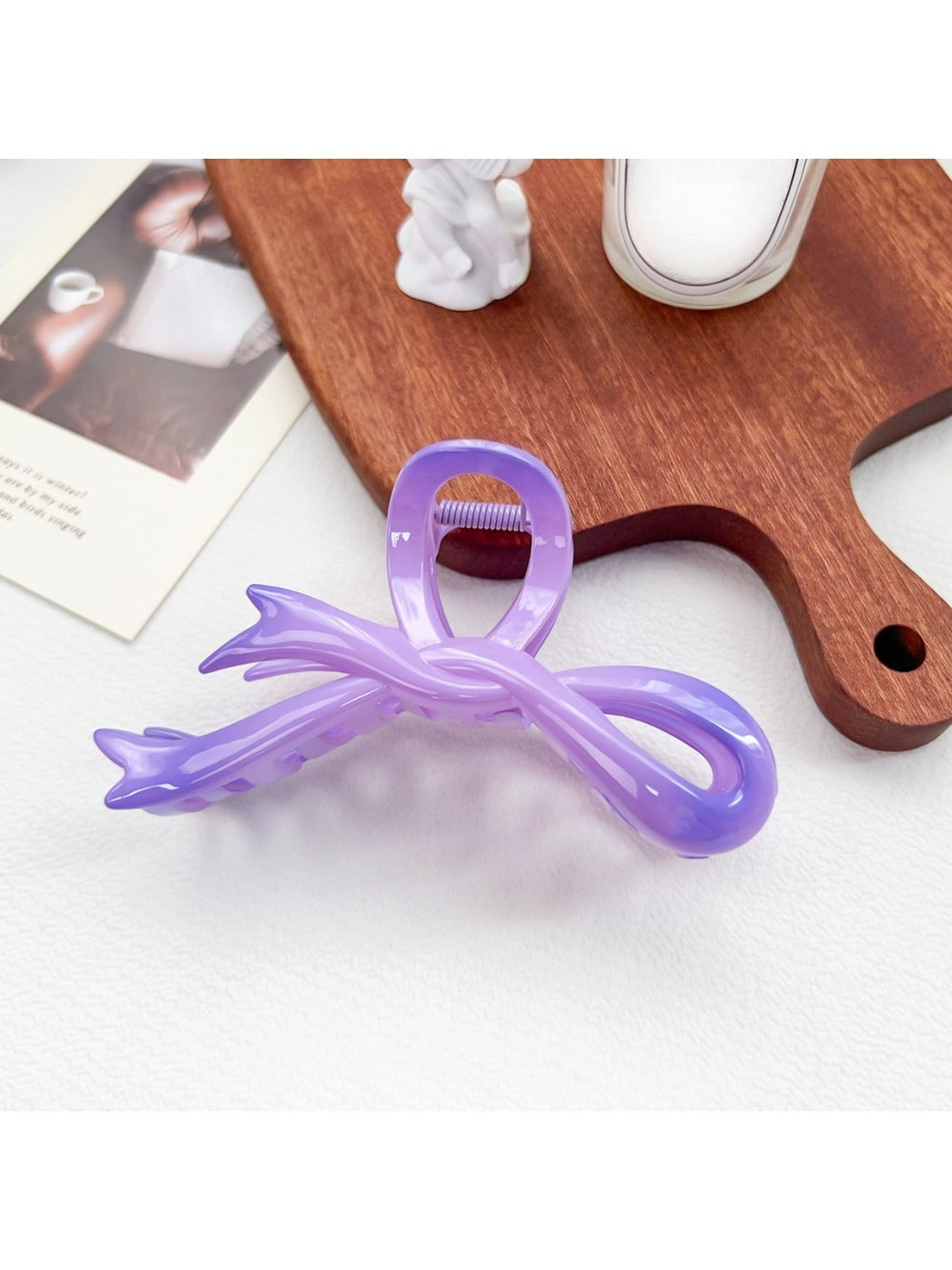 Beau heart shaped bow claw clip clipped into straight hair on a model's side profile