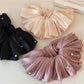 Close-up of smooth satin fabric texture on large beige scrunchie