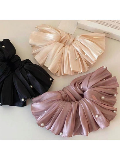 Close-up of smooth satin fabric texture on large beige scrunchie
