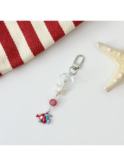 Green fish keychain hanging from a backpack zipper pull