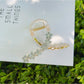 Beau flower crisscross hair claw clip on white surface with shadows