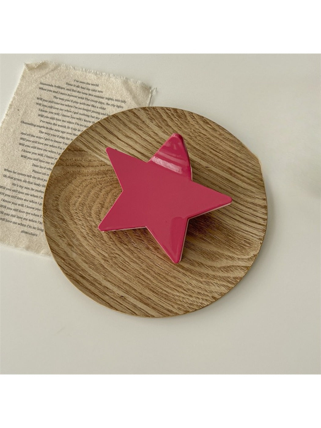 Beau star shaped claw clip resting on fabric surface for contrast