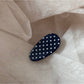 Close-up of oval hair clip with glossy finish and polka dot pattern