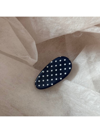 Close-up of oval hair clip with glossy finish and polka dot pattern