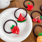 Close-up of a pink hair tie featuring a detailed strawberry charm