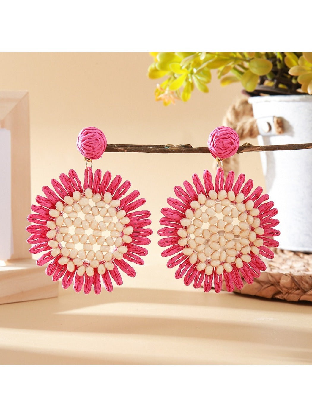 Sunflower drop earring held between fingers showing size and detail