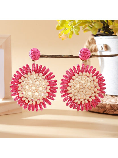 Sunflower drop earring held between fingers showing size and detail
