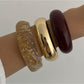 Multiple Lovra bracelets stacked together showcasing their polished metal texture