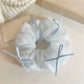 Blue tulle scrunchie styled on a wrist with bow prominently displayed
