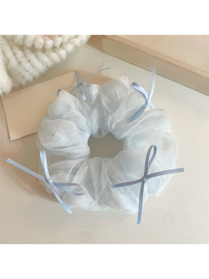 Blue tulle scrunchie styled on a wrist with bow prominently displayed