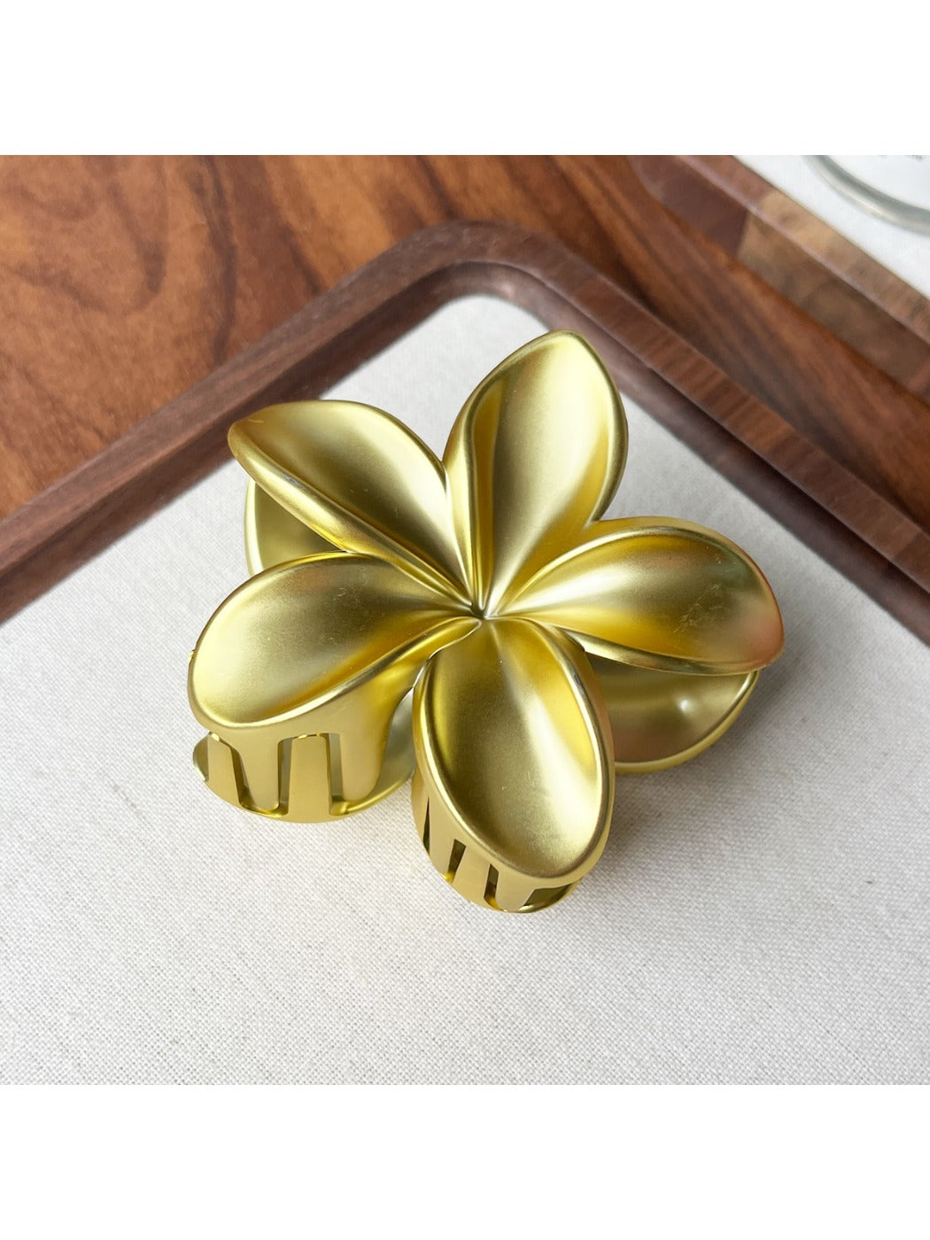 Beau flower shaped claw clip resting on fabric surface