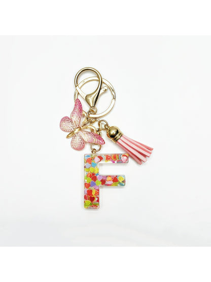 Silver keychain with butterfly and letter pendant against a pastel background