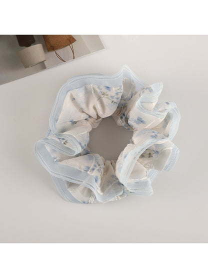 Top view of Gifty floral scrunchie with soft pink tulle ruffles and flower patterns
