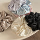 Glossy satin scrunchie styled on a wrist as a bracelet