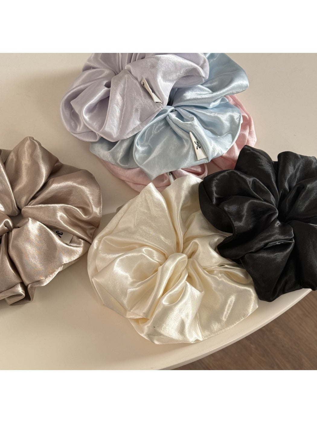 Glossy satin scrunchie styled on a wrist as a bracelet