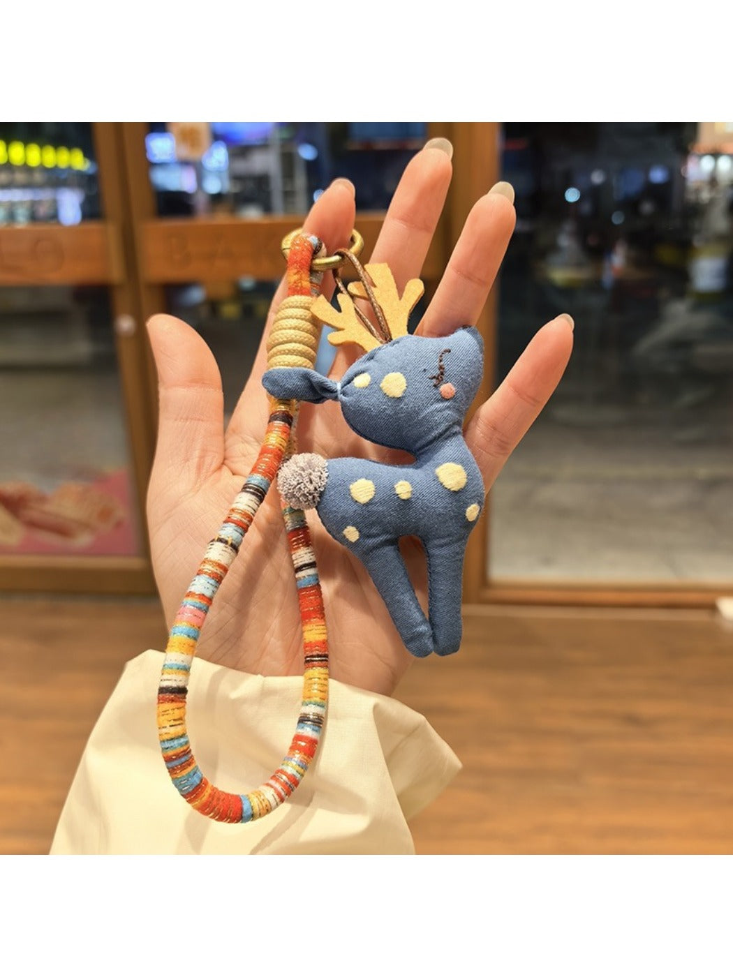 Deer charm keychain next to a notebook and pen on a desk