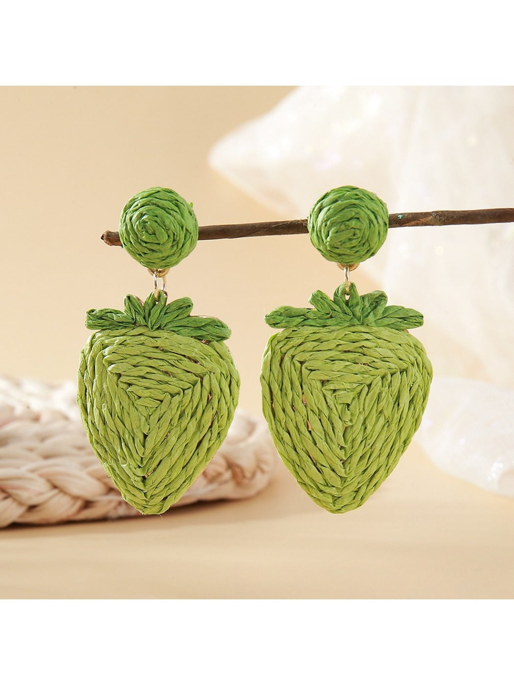 Raffia strawberry earrings placed on natural wood surface