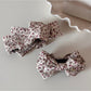 Side view of Beau small floral bow hair clip with metal clip attachment