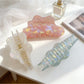 Beau holographic claw clip open, displaying inner teeth and hinge