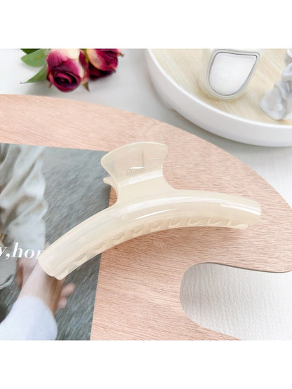 Pastel curved claw clip photographed with soft shadows on white surface