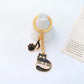 Cartoon cat piano keychain with a smiling cat face and black piano keys