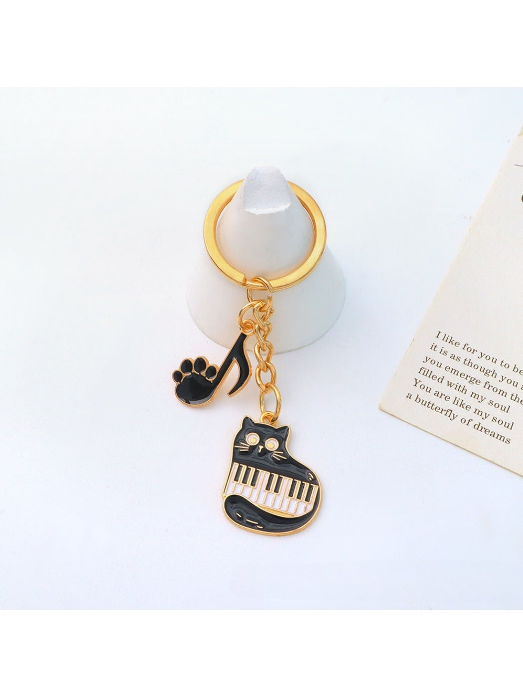Cartoon cat piano keychain with a smiling cat face and black piano keys