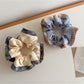 Gifty scrunchie worn on a wrist highlighting ruffle detail and multicolor pattern