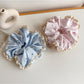 Gifty scrunchie with white polka dots and delicate lace trim on a neutral background