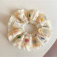 Close-up of colorful polka dot ruched scrunchie on white background
