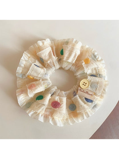 Close-up of colorful polka dot ruched scrunchie on white background