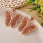 Butterfly drop earrings hanging from a jewelry stand with natural lighting